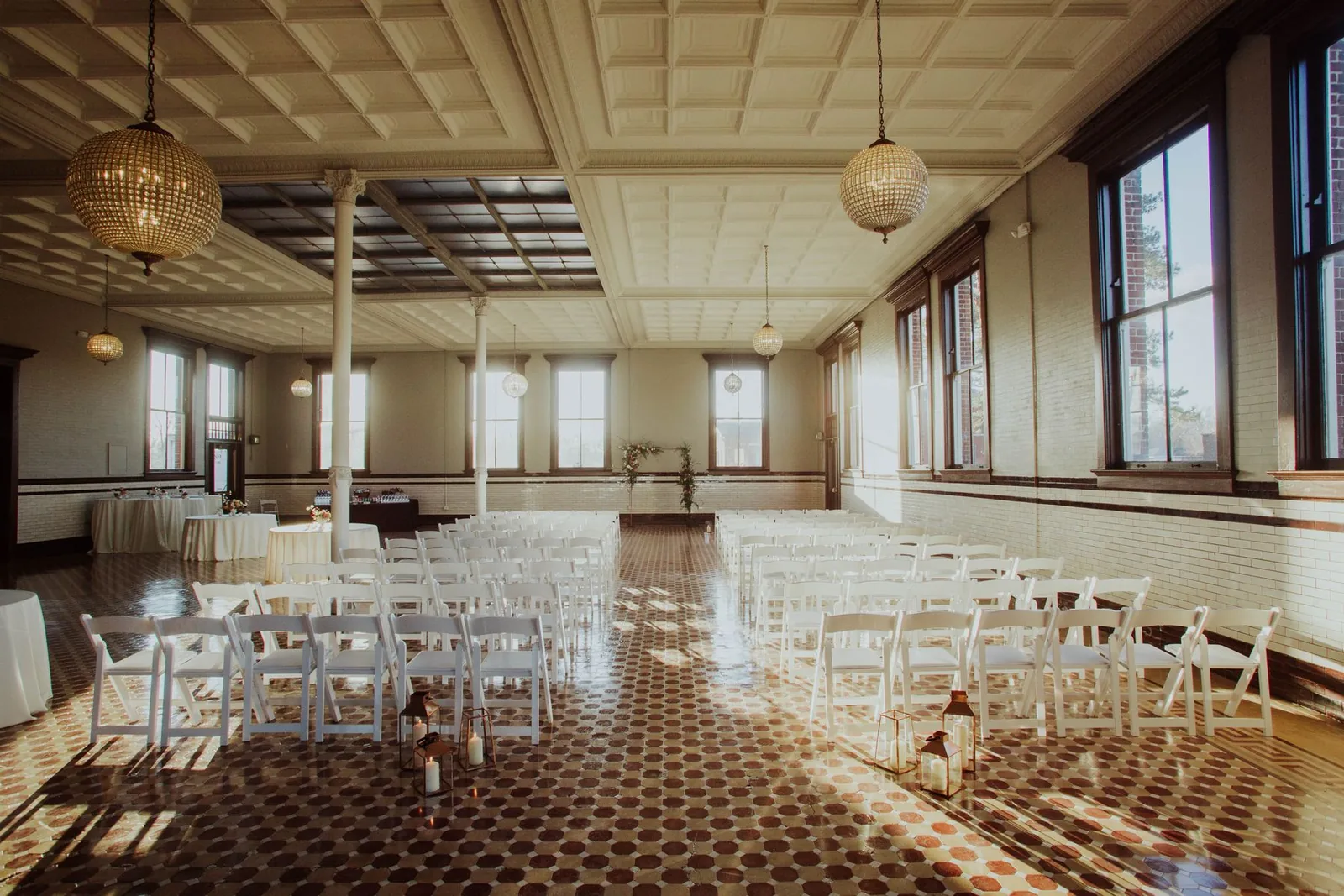 Rows of ceremony chairs beneath chandeliers in a light-filled hall
