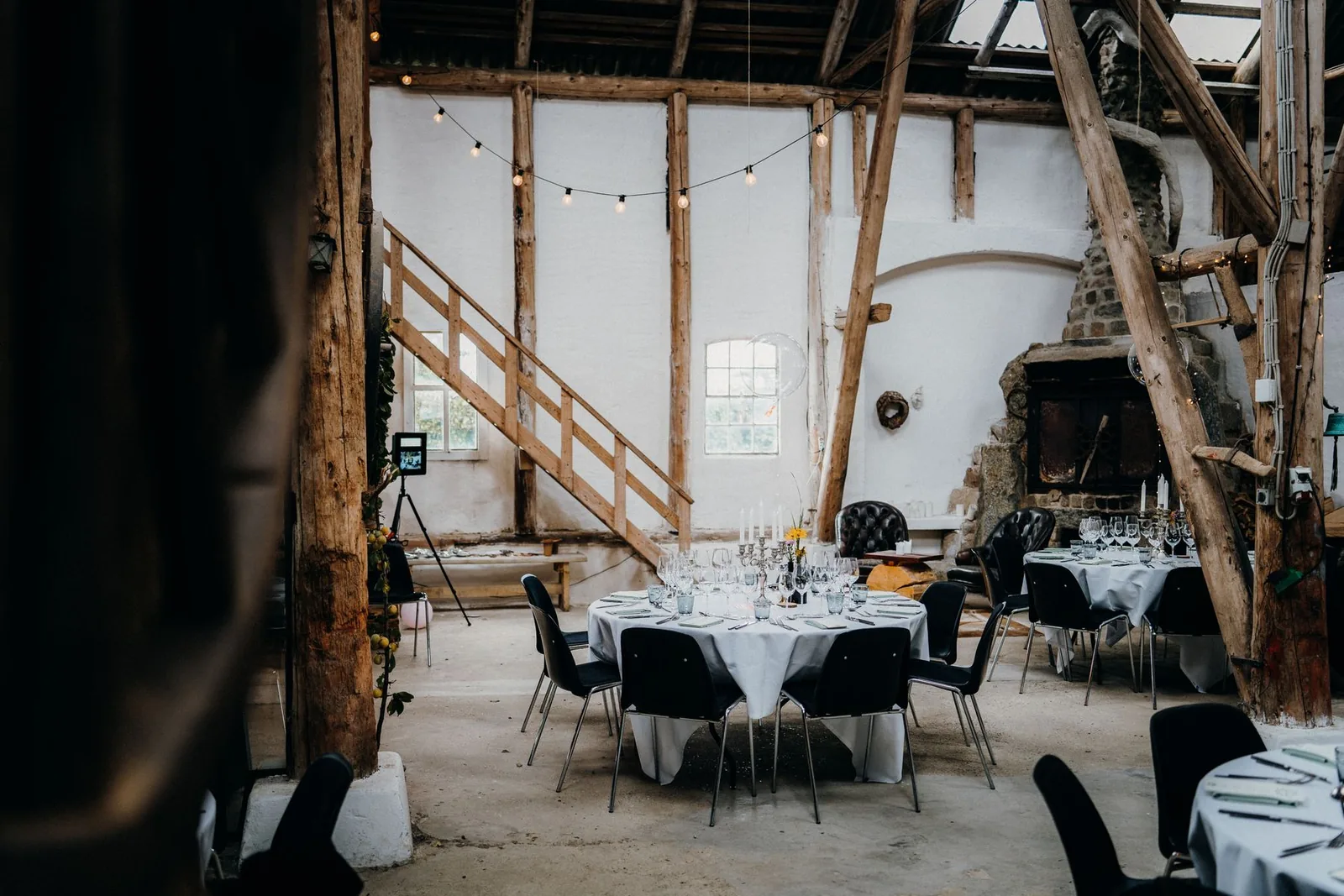 Wedding reception tables beneath rustic timber beams