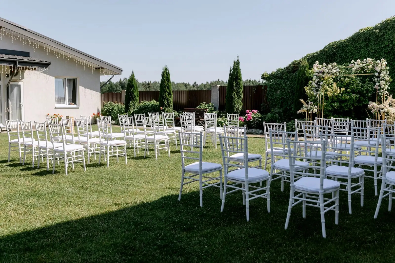 White reception chairs and tables arranged on a green lawn