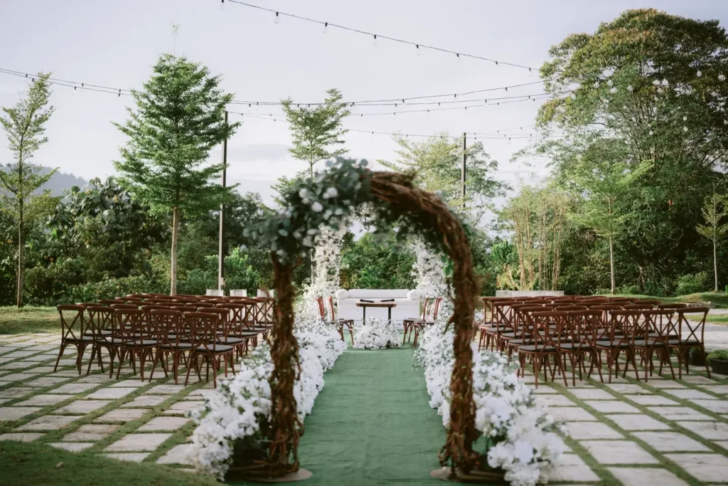 Outdoor ceremony chairs facing a floral arch in a leafy garden